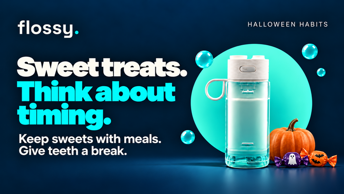 Flossy water flosser beside a small pumpkin and wrapped sweets on the established navy background.